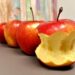 Apples in a row with first apple eaten to the core.