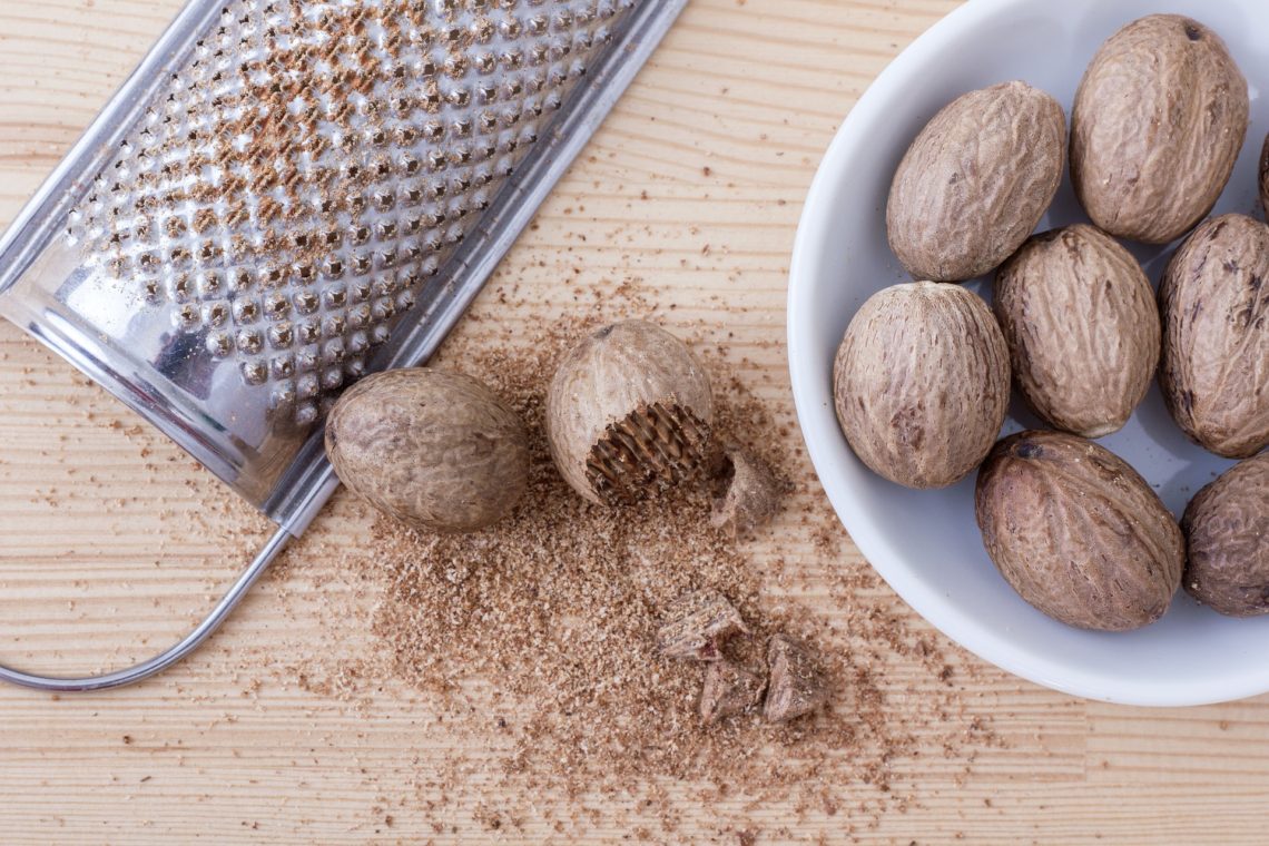 Whole Nutmeg, grater, and grated nutmeg on a table