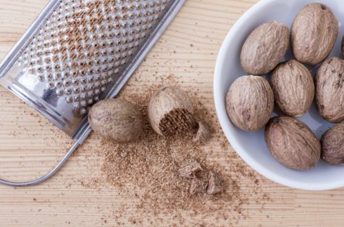 Whole Nutmeg, grater, and grated nutmeg on a table