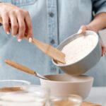 baker spooning flour into bowl