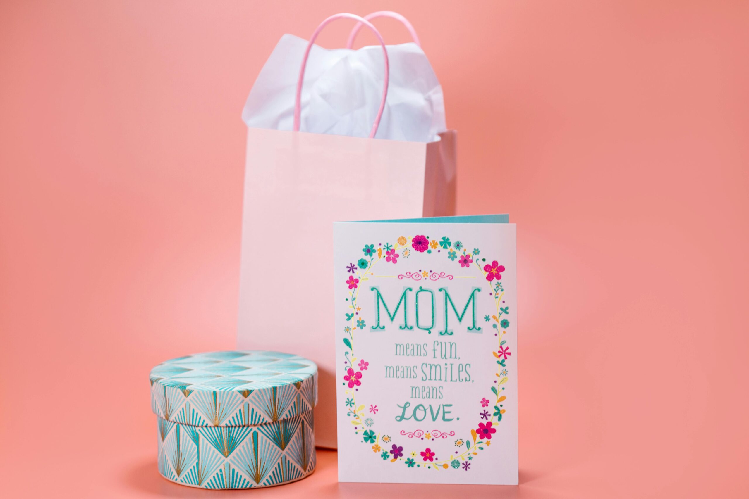 Mother's Day gift bag, gift box, and card on pink background.
