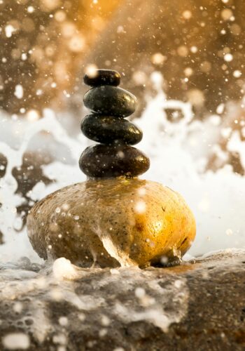 Stacked Pebbles splashed with water, bathed in natural light.