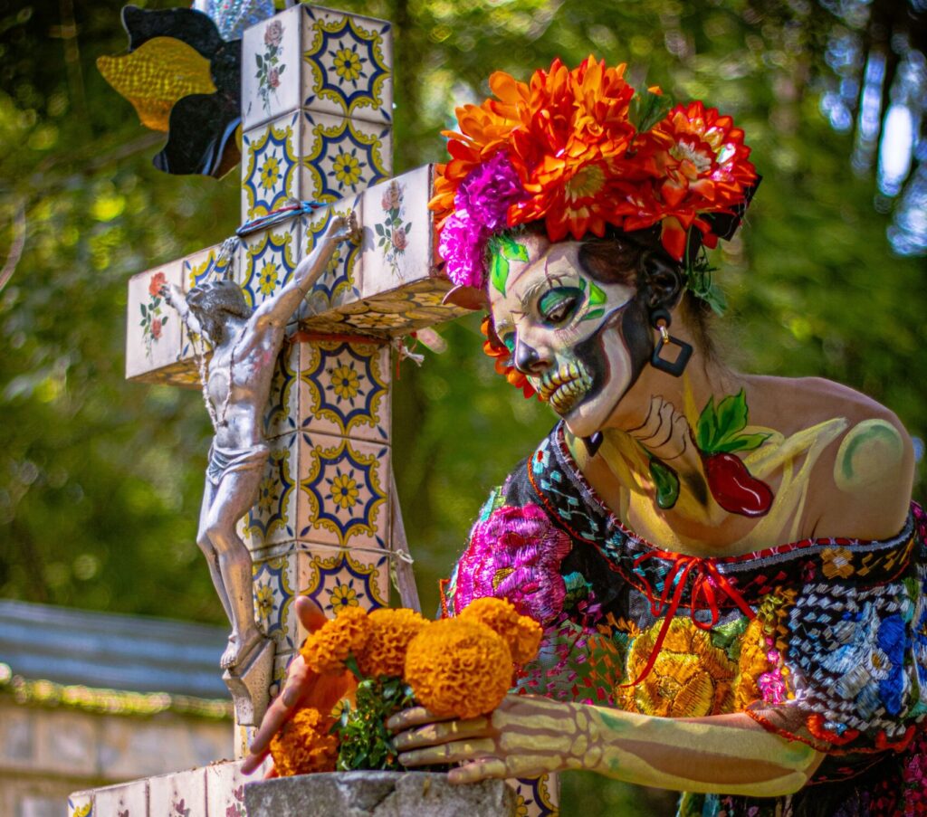 A Caterina painted person at a cemetery decorated for the day of the dead.